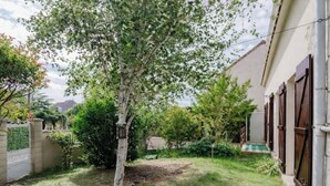 A residential property with a fenced yard, a tree, and a building with wooden shutters. - Chic House a 15 minutes of paris  (Argenteuil)