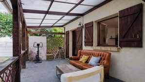 A covered outdoor seating area with a sofa and armchair, a small table, and a metal stool. - Chic House a 15 minutes of paris  (Argenteuil)