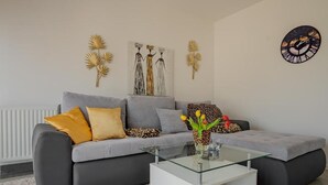 A modern living room with a grey sofa, a glass coffee table, and decorative wall art.