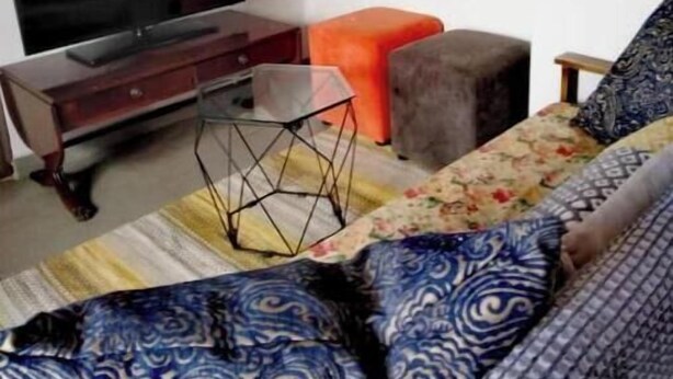 Una sala de estar con un sofá, un televisor y un adorno de pared.