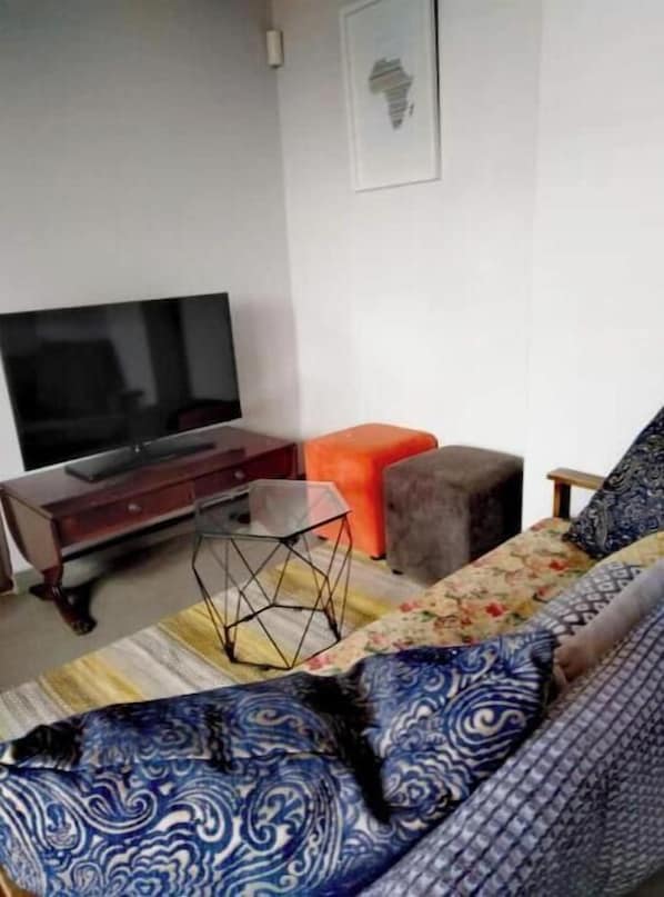 A living room with a sofa, a television, and a decorative wall piece.