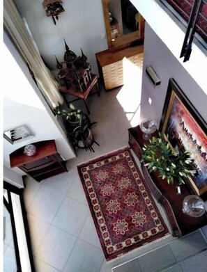 A staircase with a red patterned rug leading to a room with a wooden cabinet and a framed picture.