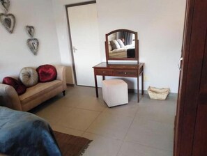 A bedroom with a bed, a dresser, a mirror, and a door.