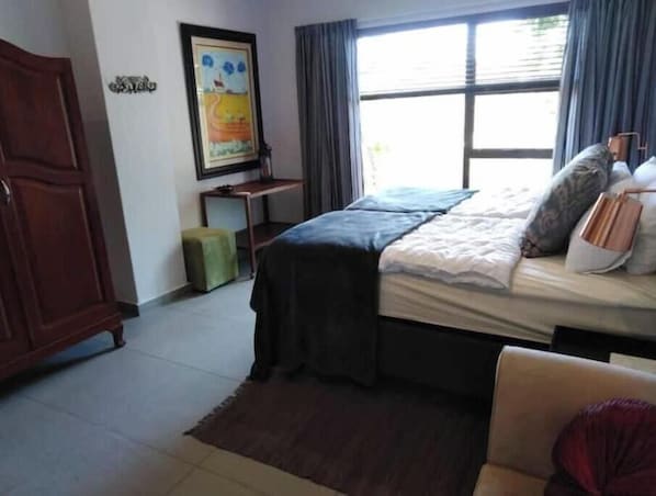 A bedroom with a bed, a desk, a chair, and a wardrobe.