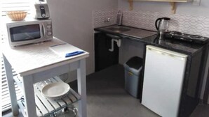 Cocina compacta con microondas, lavamanos y refrigerador pequeño.