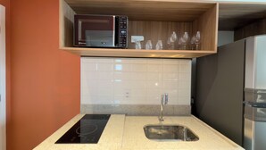 Eine moderne Küche mit integriertem Mikrowellenherd, einer Spüle und einem Holzregal über der Arbeitsplatte.