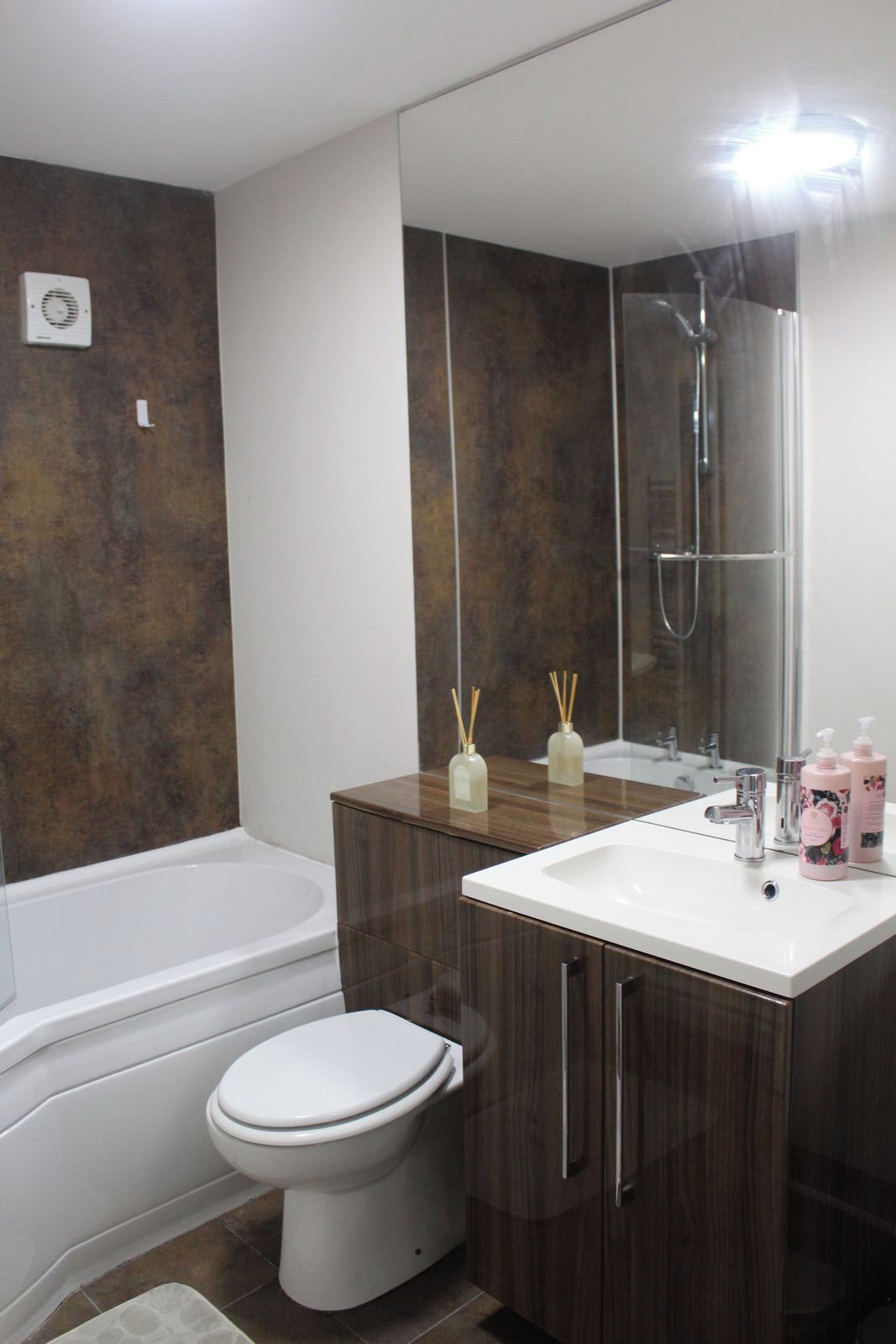 Een moderne badkamer met een bad, toilet en wastafel met spiegel.