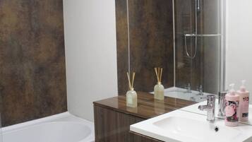 Een moderne badkamer met een bad, toilet en wastafel met spiegel.