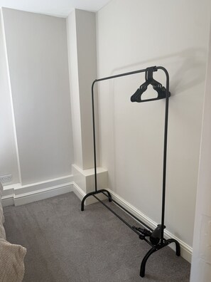 Ein Eckzimmer mit einem schwarzen, metallenen Kleiderständer vor einer weißen Wand.