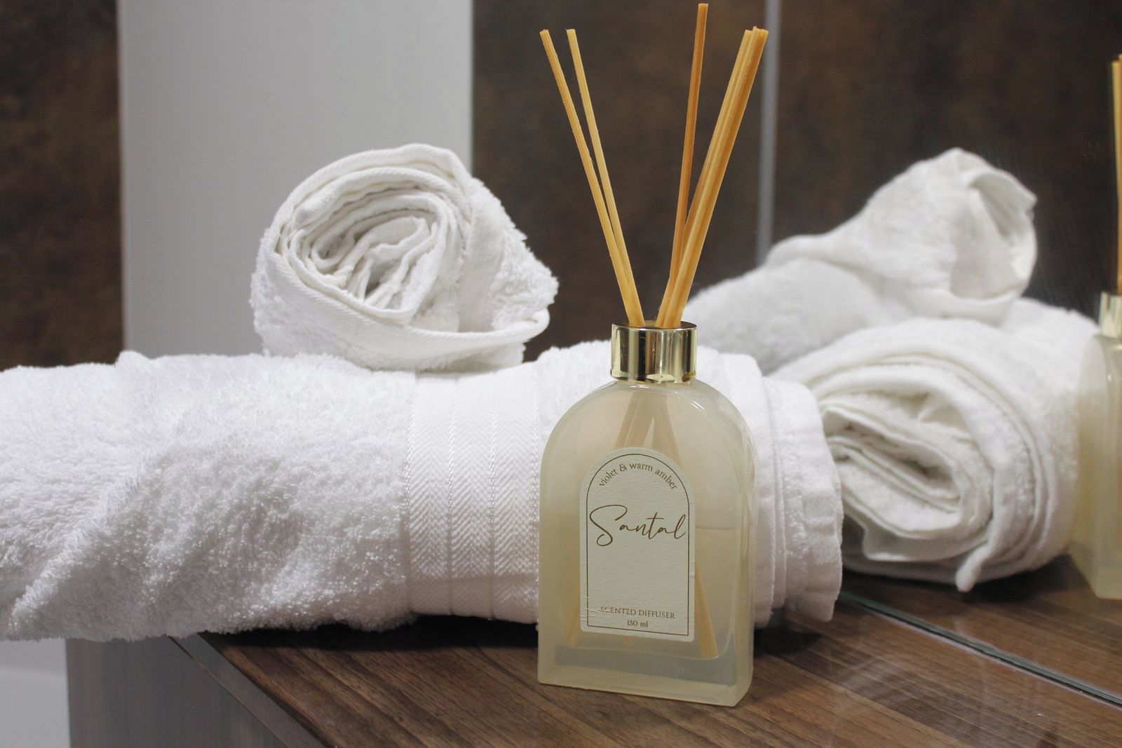 Ein Badezimmer mit einem weißen Handtuch, einem Santal-duftenden Diffusor und Schilff diffusoren.
