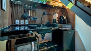 Een kleine keuken met een spoelbak, kookplaat en verschillende keukengerei.