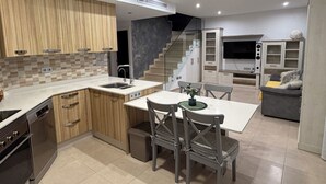 A modern kitchen with wooden cabinets, a built-in oven, and a dining area with chairs and a table. - Villa Soleada - Private Pool - Beach 10 minutes away (San Pedro del Pinatar)