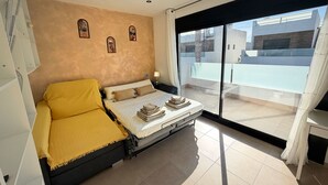 A bedroom with a bed, a sofa, a small table, and a window with a view of buildings. - Villa Soleada - Private Pool - Beach 10 minutes away (San Pedro del Pinatar)
