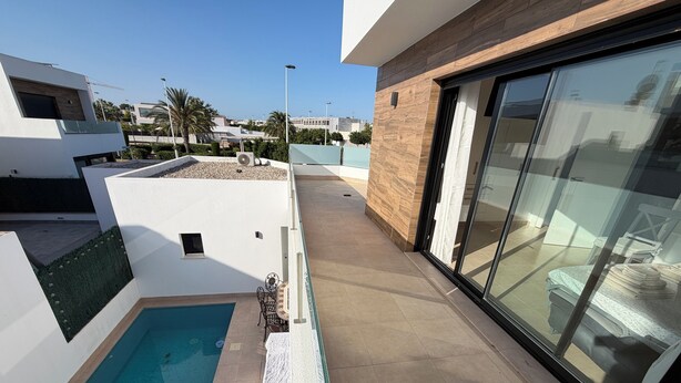 A modern outdoor pool area with a glass door leading to a balcony, surrounded by a white wall and a wooden panel. - Villa Soleada - Private Pool - Beach 10 minutes away (San Pedro del Pinatar)