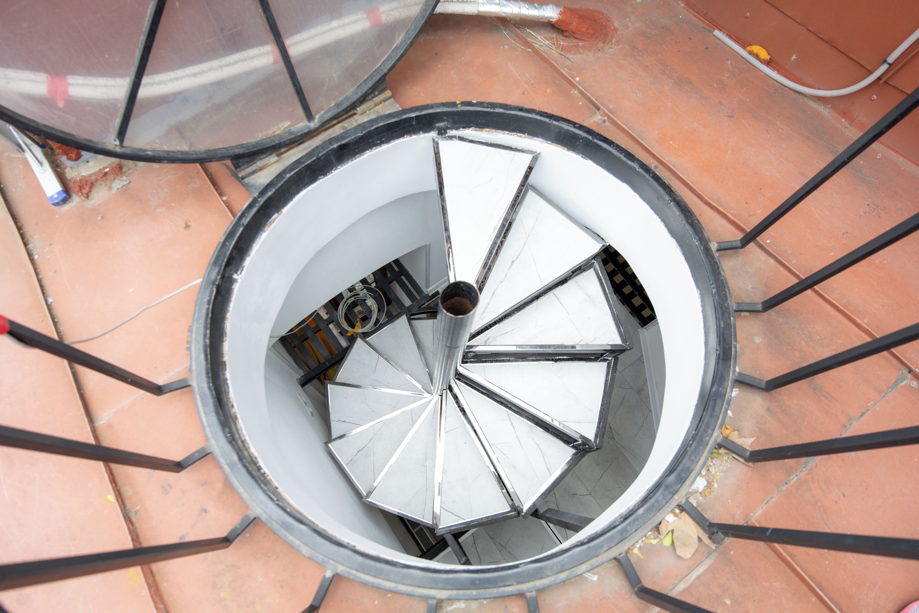 A spiral staircase with a metal railing and a circular opening at the top.