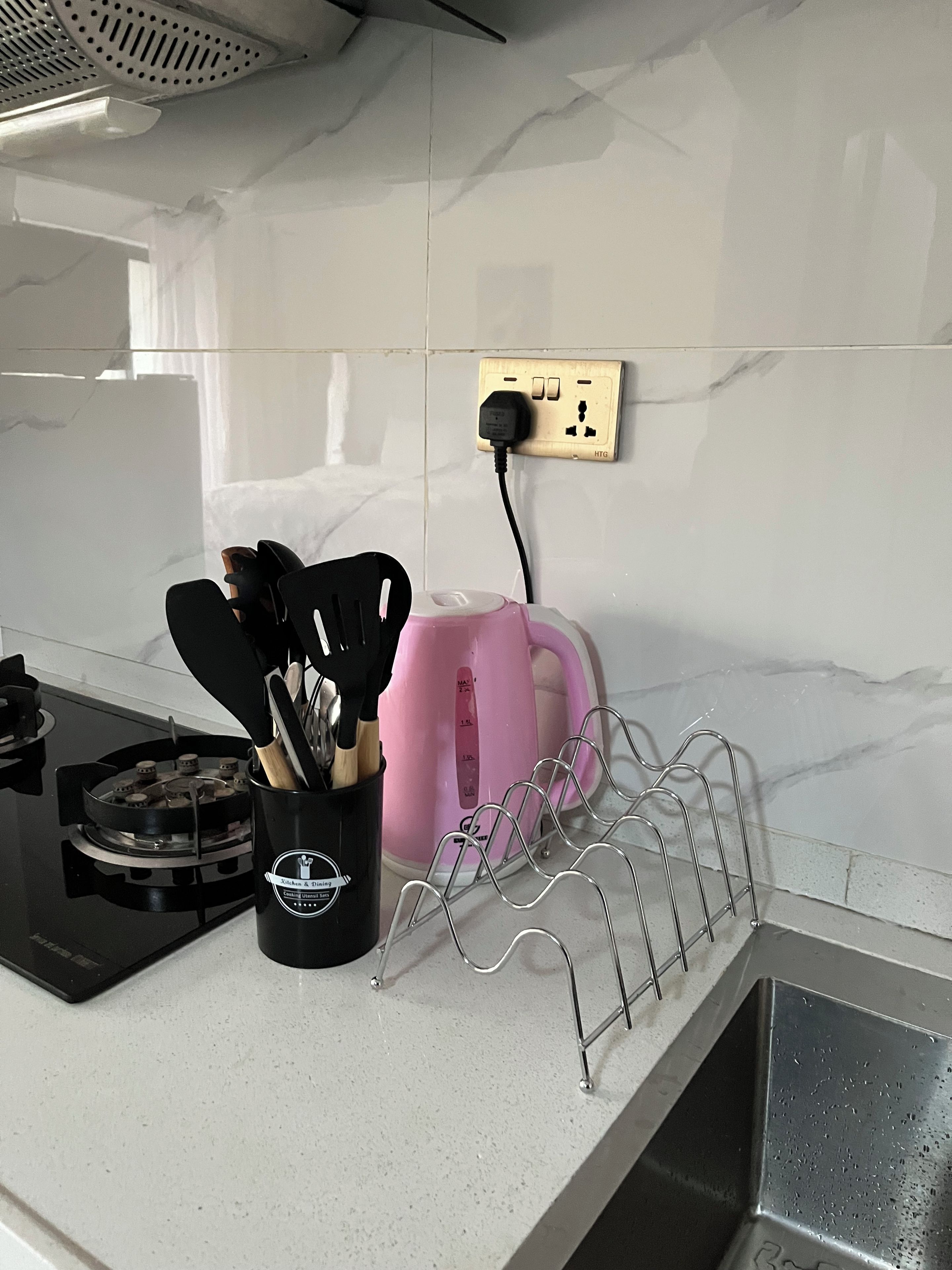 A kitchen with a gas stove, a pink toaster, and a utensil holder on the counter.