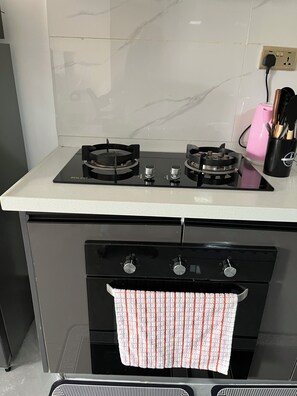 Eine Küche mit einem Gaskochfeld, einem schwarzen Backofen und einer Edelstahl-Arbeitsplatte.