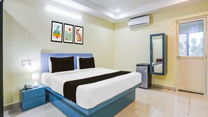 Camera d'albergo con un letto, comodino, lampada, climatizzatore e uno specchio.