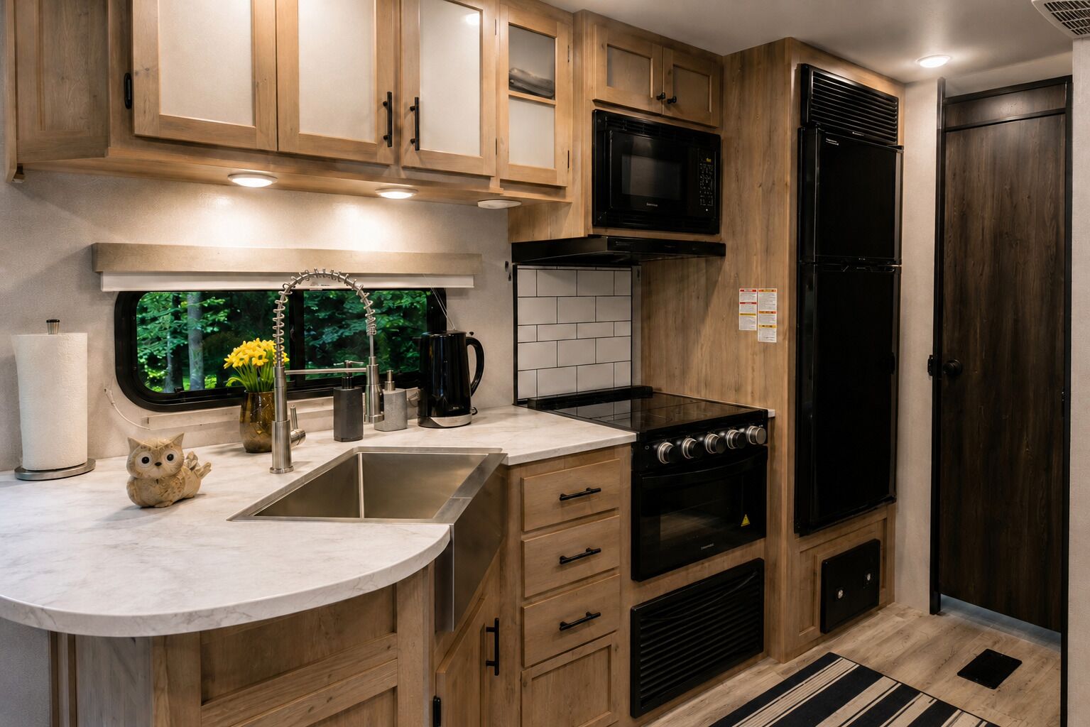Une cuisine compacte avec des meubles en bois, un évier en acier inoxydable, une cuisinière noire et un four à micro-ondes.