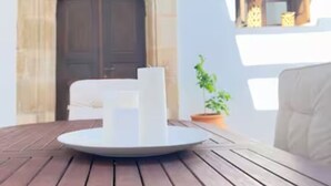 Une table en bois sur laquelle se trouve un objet blanc, une cheminée en pierre et une plante en pot.