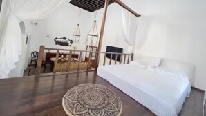Une chambre à coucher avec un lit, une table en bois, une chaise, un téléviseur et un ventilateur de plafond.