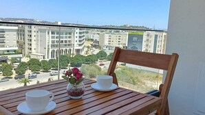 A wooden table with two white cups and a vase of flowers on a balcony overlooking a cityscape. - Dream Apartment in Jardins de Carthage (Résidence luxoria)