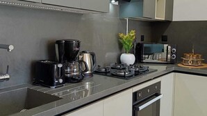 A modern kitchen with a black countertop, stainless steel appliances, and white cabinetry. - Dream Apartment in Jardins de Carthage (Résidence luxoria)