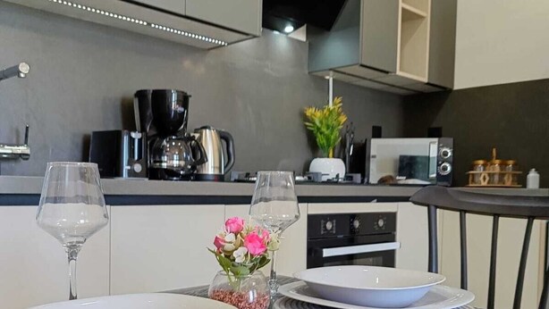 A modern kitchen with a dining table set for two, a coffee machine, and a microwave. - Dream Apartment in Jardins de Carthage (Résidence luxoria)