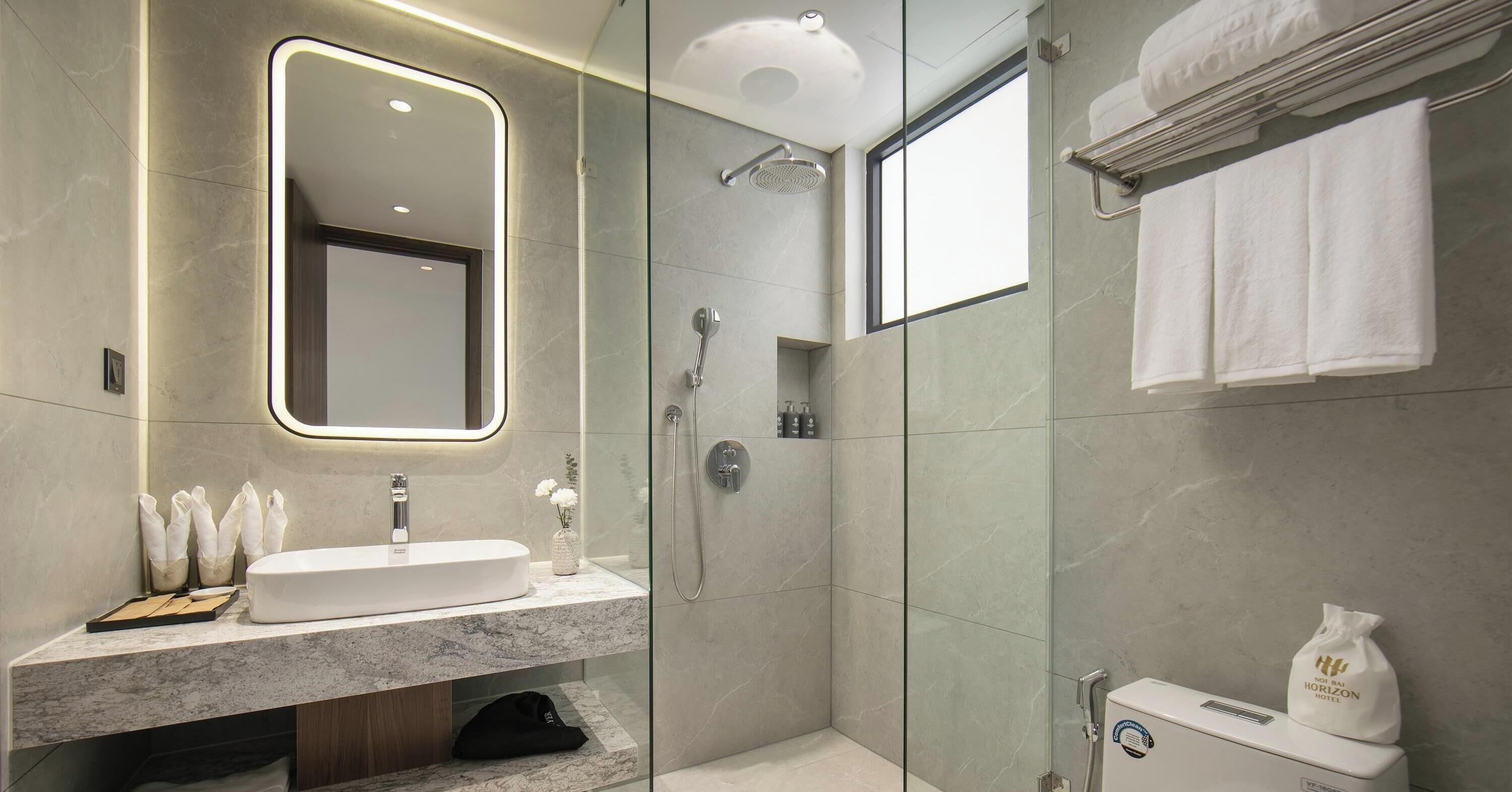 A modern bathroom with a glass shower enclosure, a vanity with a sink, and a towel rack.
