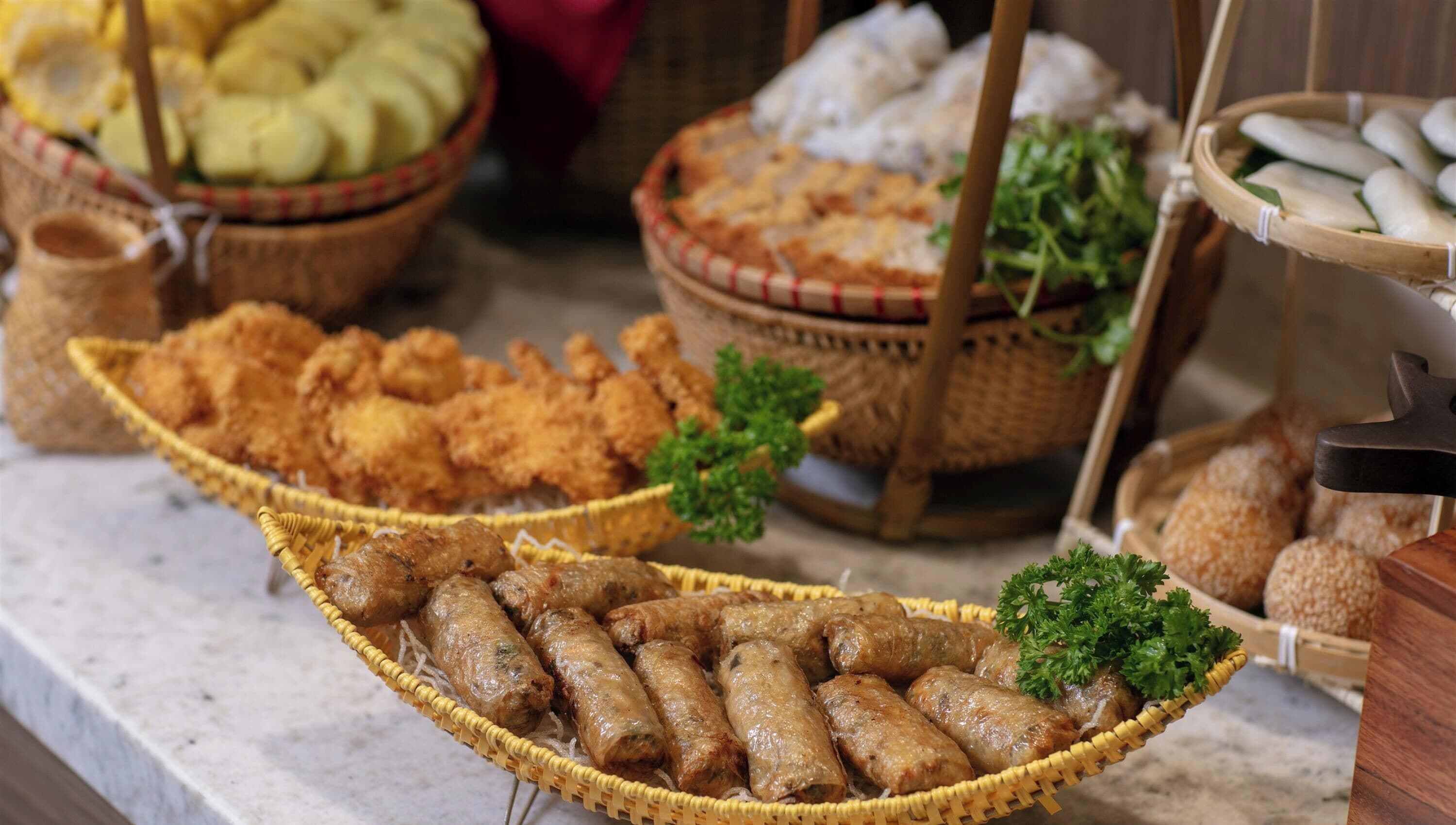 Diversos alimentos expostos em cestas, incluindo comidas fritas e pães.