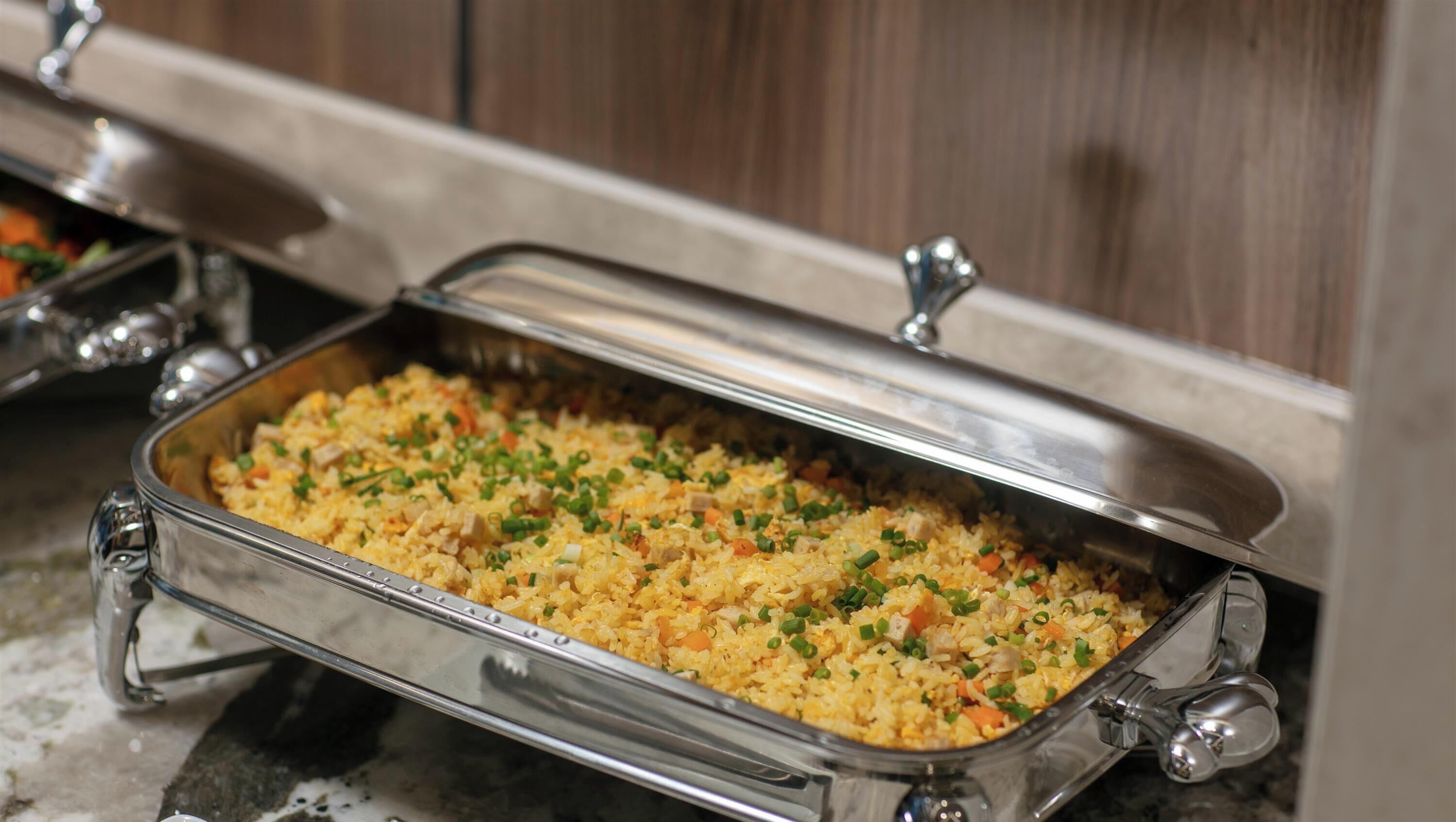 Un buffet avec un plat de service couvert contenant du riz frit.