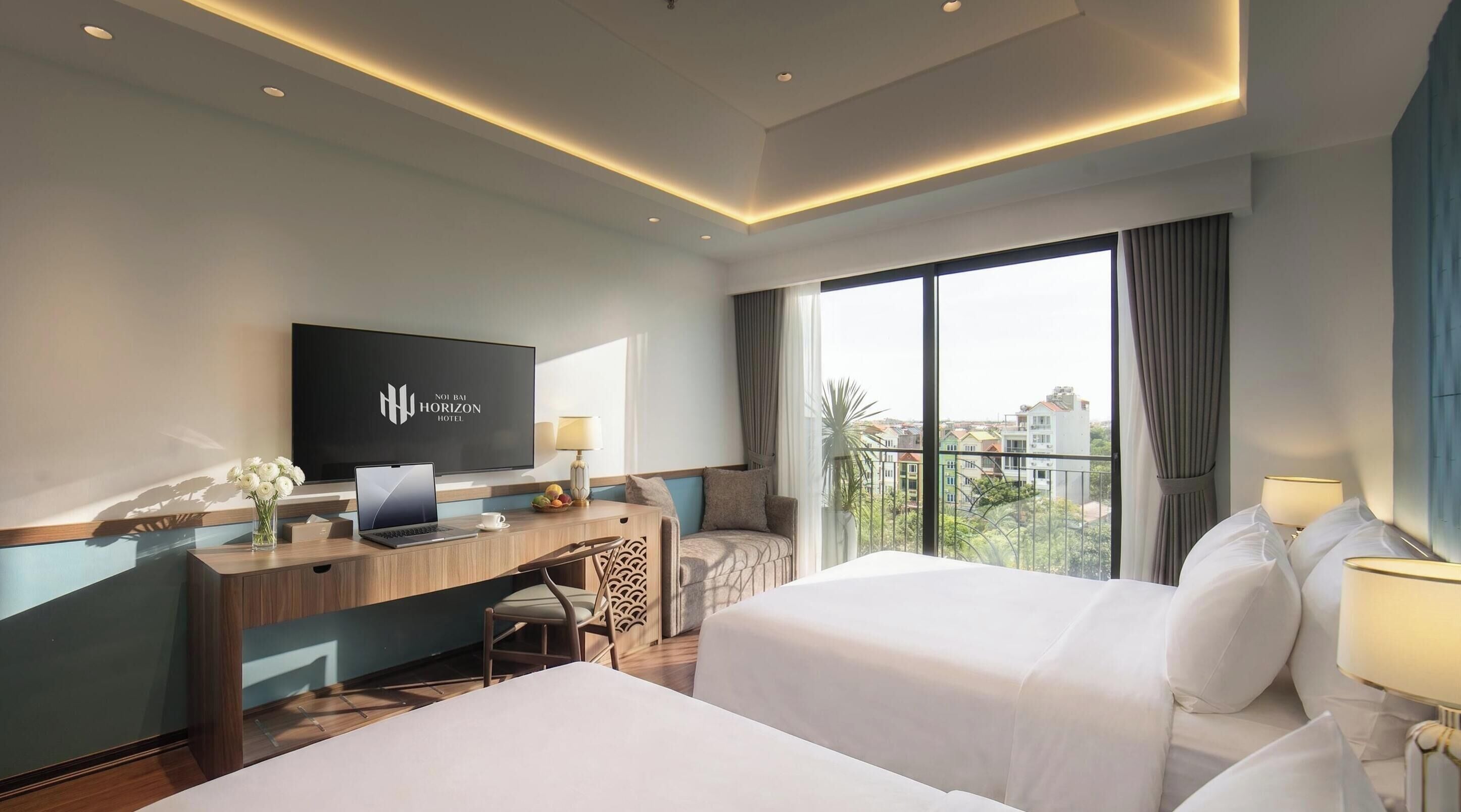 Une chambre d’hôtel avec un lit, un bureau avec un ordinateur portable, une télévision et une vue sur la ville.