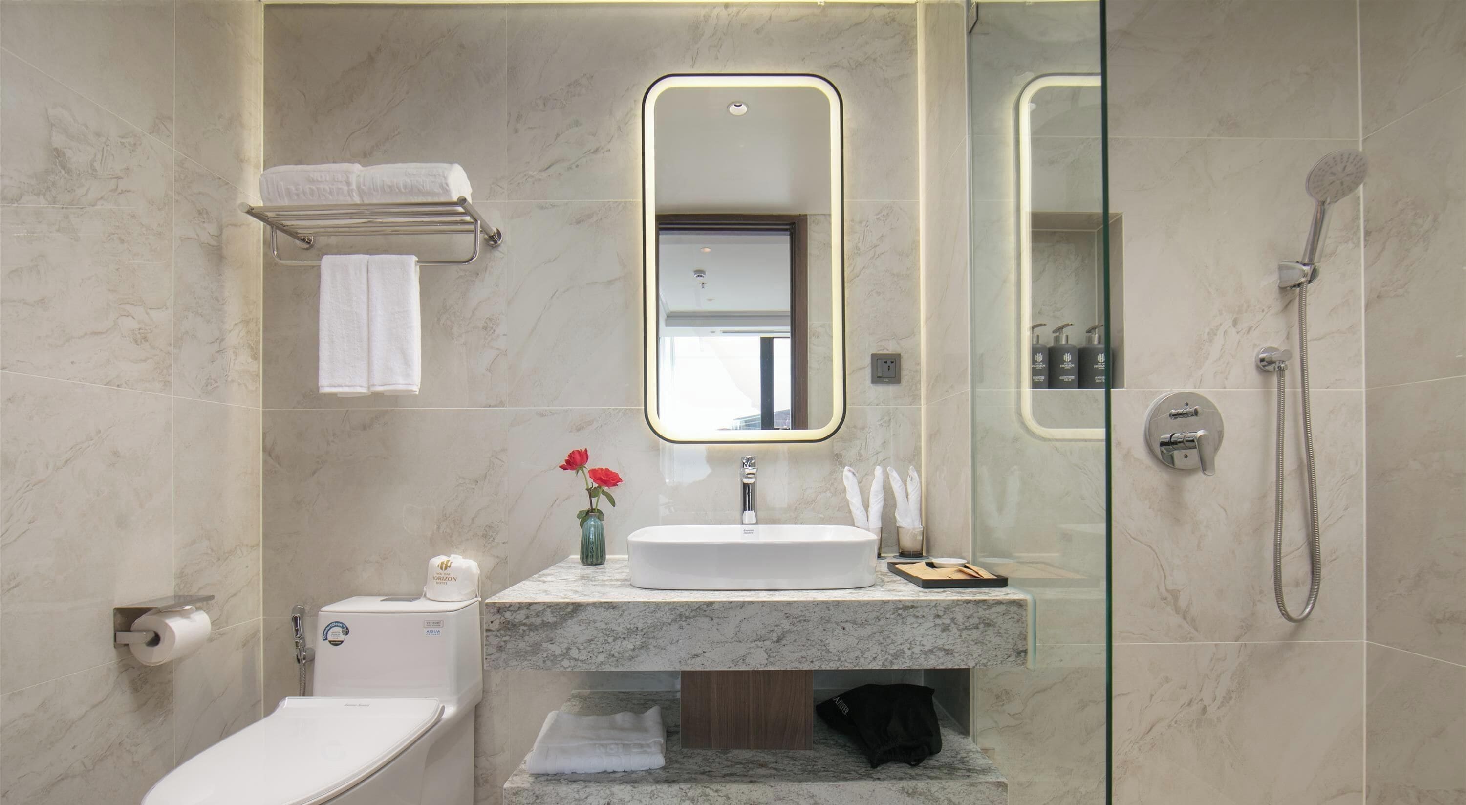 Une salle de bain moderne équipée de toilettes, d’un lavabo, d’un miroir et d’une douche.