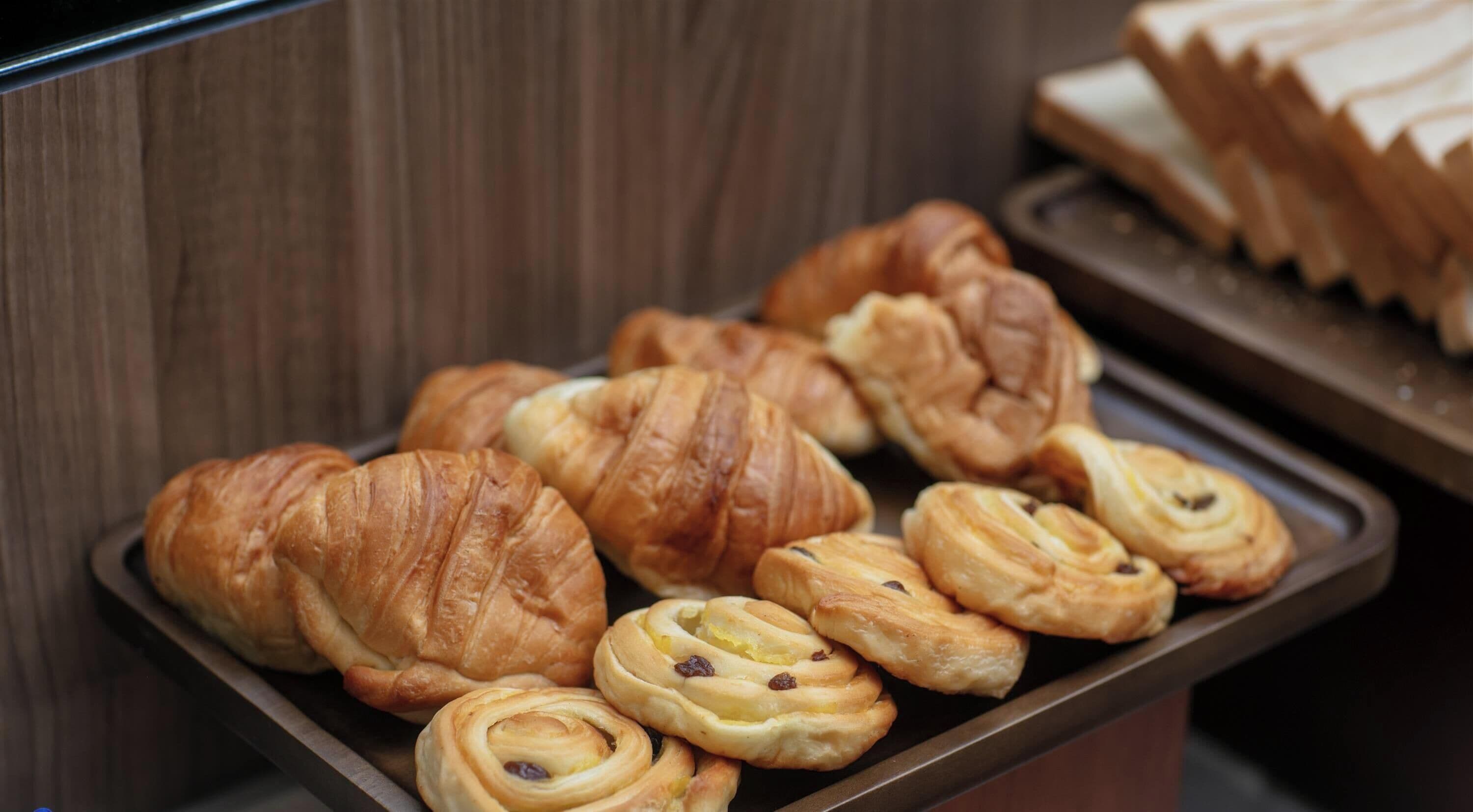 Een dienblad met diverse gebakjes, waaronder croissants en kaneelbroodjes.