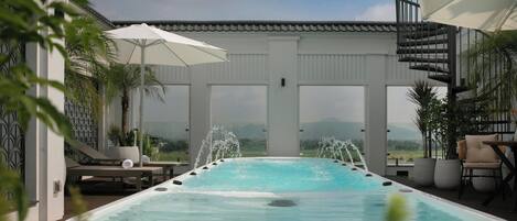 Un jacuzzi con vistas al paisaje, rodeado de sillas de descanso y sombrillas.