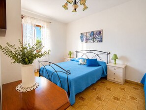 A bedroom with a bed, bedside tables, a nightstand, a potted plant, and a painting on the wall. - House with a view of the sea, sunsets over Corsica and Pianosa, 700 meters from Spiaggia degli Stecchi (Capoliveri)