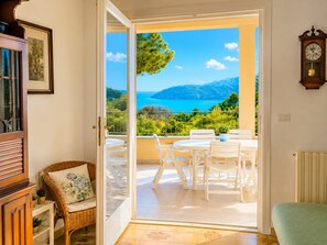 A room with a sliding glass door leading to an outdoor patio with a table and chairs, a wicker chair, and a radiator. - House with a view of the sea, sunsets over Corsica and Pianosa, 700 meters from Spiaggia degli Stecchi (Capoliveri)