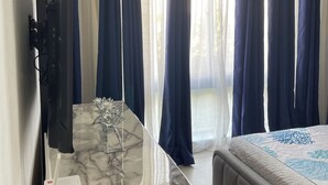 A bedroom with a bed, a TV, a marble table, and curtains. - Haven Escape  2-bedroom condo with AC and private beach access in Punta Cana (Punta Cana)
