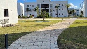 A modern building with a paved walkway, a number '9' sign, and a clear blue sky. - Haven Escape  2-bedroom condo with AC and private beach access in Punta Cana (Punta Cana)