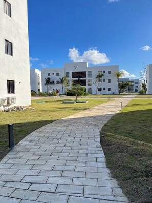 Un bâtiment moderne avec un trottoir dallé, une enseigne portant le chiffre « 9 » et un ciel bleu dégagé.