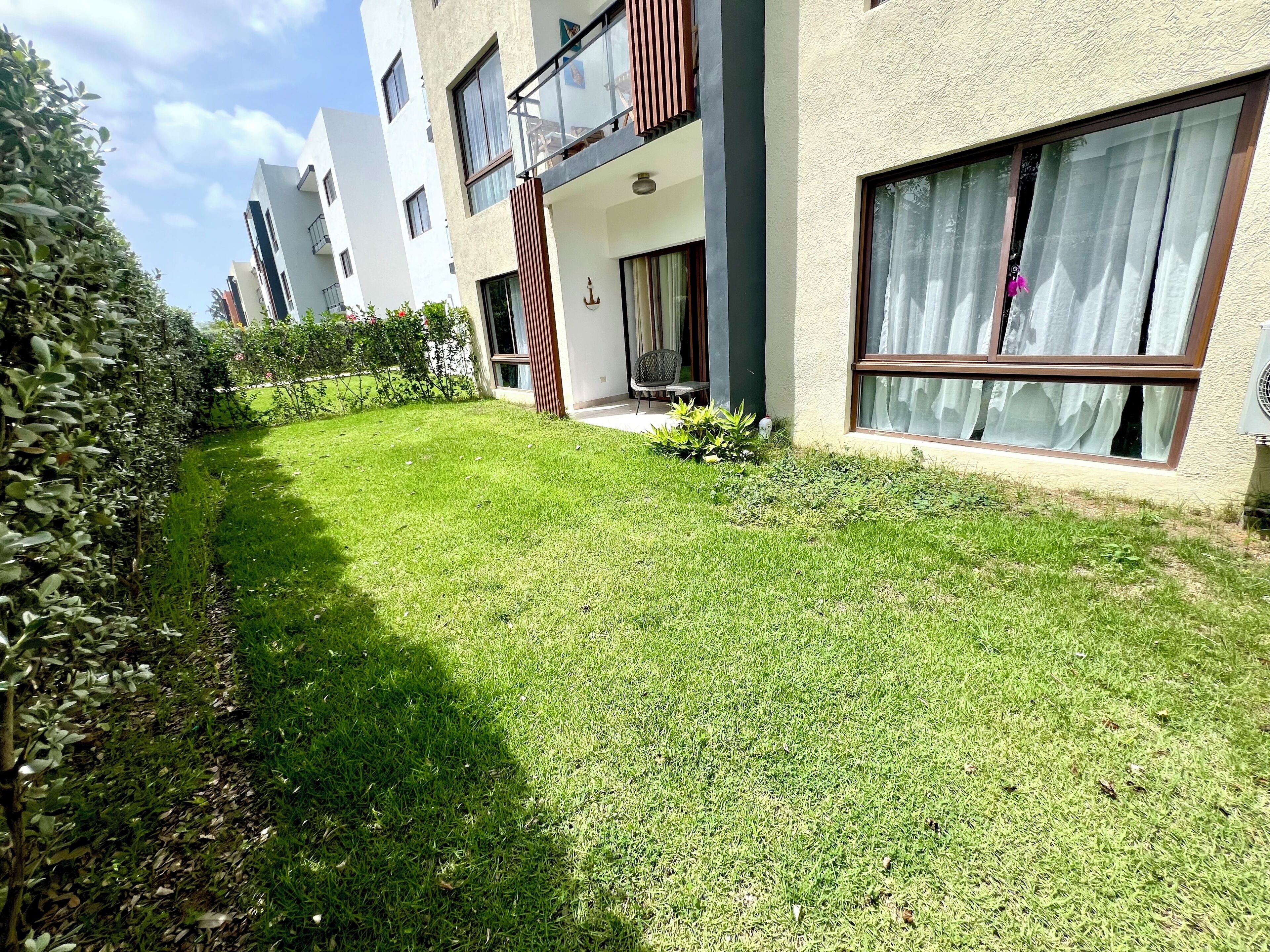 Ein Wohngebäude mit gepflegtem Rasen, einem Balkon mit Geländer und einem Fenster mit Vorhängen.