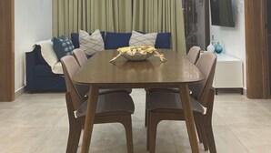 A modern dining area with a wooden table, chairs, a decorative bowl, a sofa with cushions, a television, and an air conditioning unit. - Haven Escape  2-bedroom condo with AC and private beach access in Punta Cana (Punta Cana)