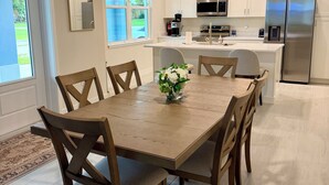Eine moderne Küche mit weißen Schränken, einem Edelstahlkühlschrank und einem Essbereich mit Holztisch und Stühlen.
