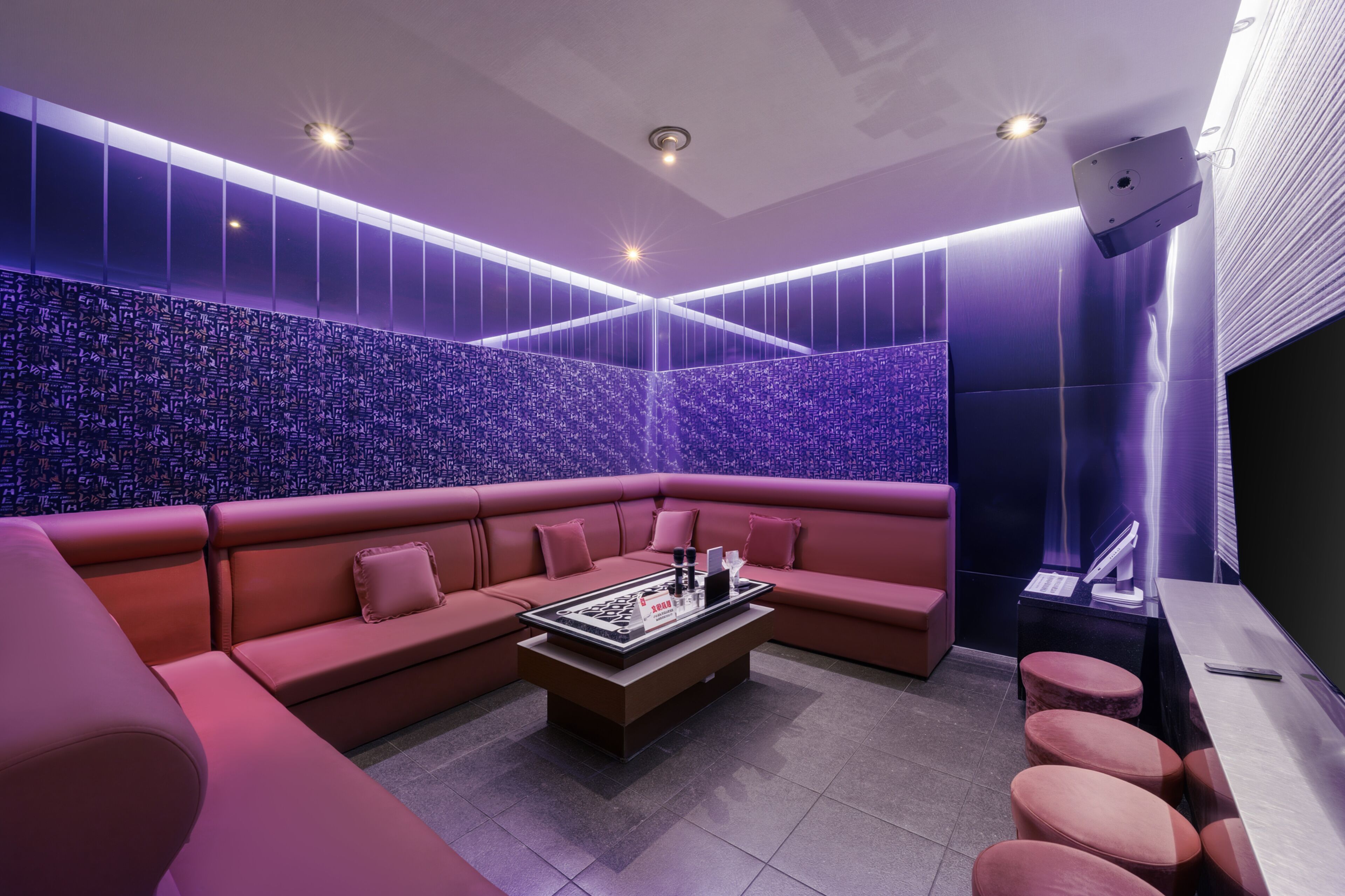 A modern lounge with a sectional sofa, a coffee table, and a wall with a unique pattern.