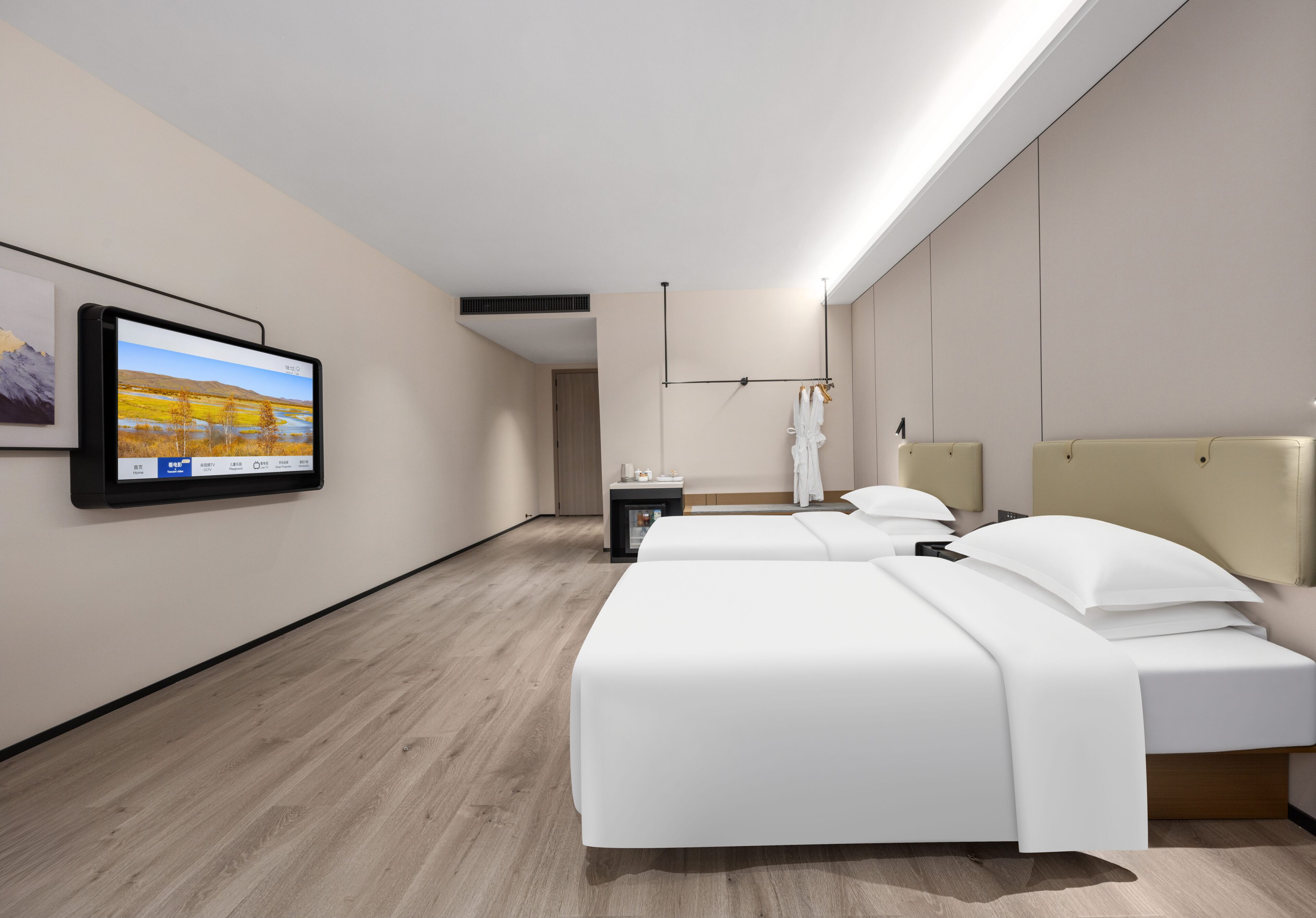 A hotel room with two beds, a TV mounted on the wall, a bedside table, and a mirror.