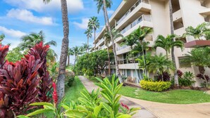 A multi-story hotel with balconies, surrounded by palm trees and tropical plants. - Brand-New Interior, 5-Min Walk to Beach, 2 Baths (Kihei)