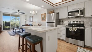 A modern kitchen with a central island, stainless steel appliances, and a view to the outdoors. - Brand-New Interior, 5-Min Walk to Beach, 2 Baths (Kihei)