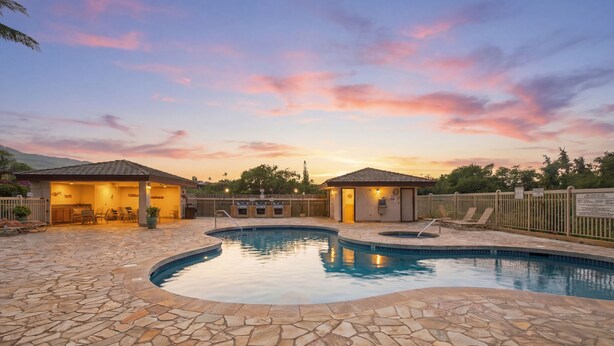 A swimming pool with stone tiles, two small buildings with roofs, and a fenced area with chairs. - Brand-New Interior, 5-Min Walk to Beach, 2 Baths (Kihei)