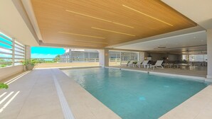 Ein modernes Hallenbad mit Holzbalkendecke, sonnendurchfluteten Bereichen und Liegestühlen.