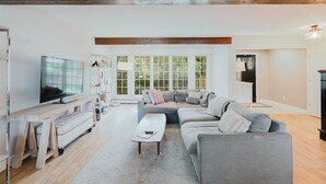Un salon moderne avec un canapé gris, une table basse en bois et un téléviseur posé sur un meuble.